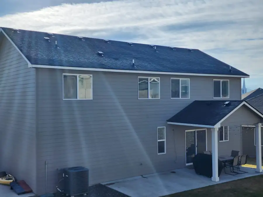 Two-storey grey home with a new dark roof and a covered back patio