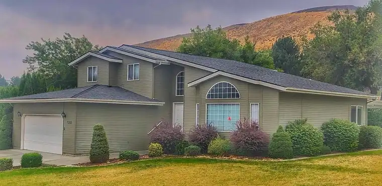 Two-storey home with hills behind it under a new shingle roof