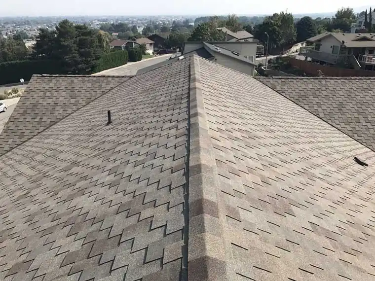 Looking along the ridge of a new shingle roof with homes below