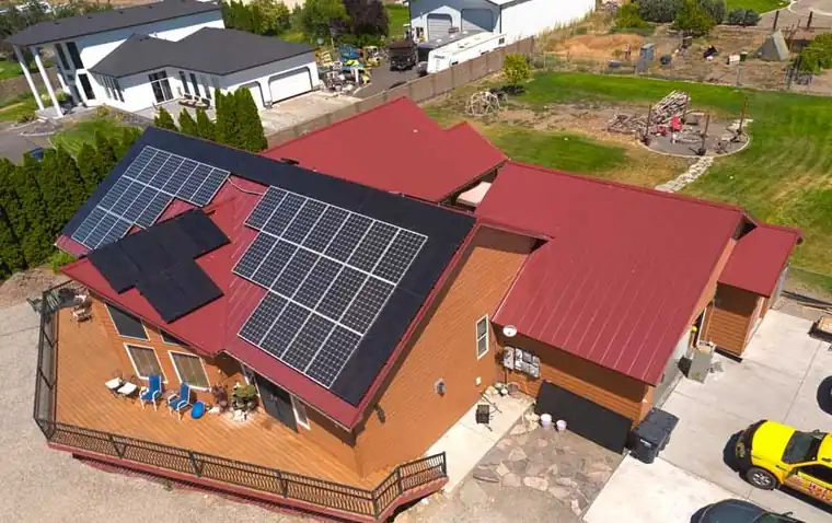 Drone view of a red standing-seam metal roof with solar panels